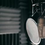 Close-up of a condenser microphone with pop filter in a professional sound studio.