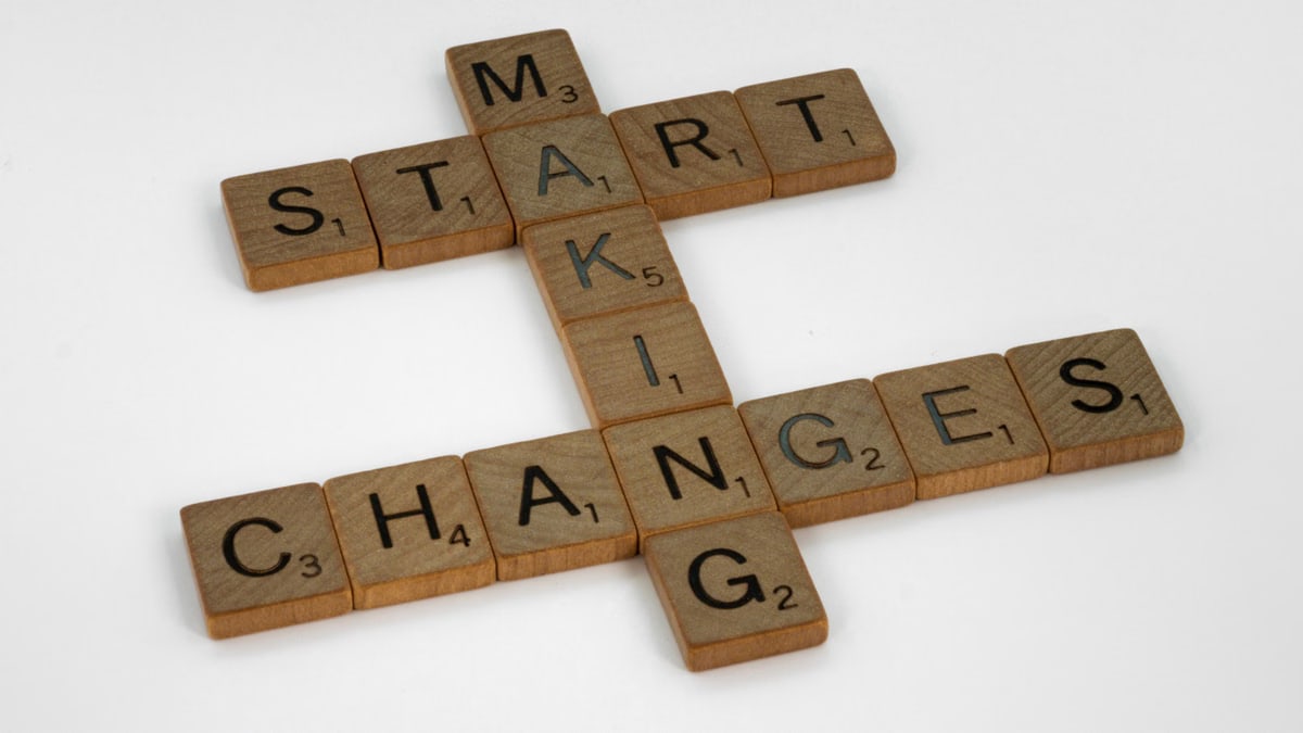 Top view of Scrabble tiles forming the phrase 'Start Making Changes' on a white background.