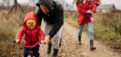 Family enjoying a joyful autumn walk along a rustic dirt road in vibrant outfits.