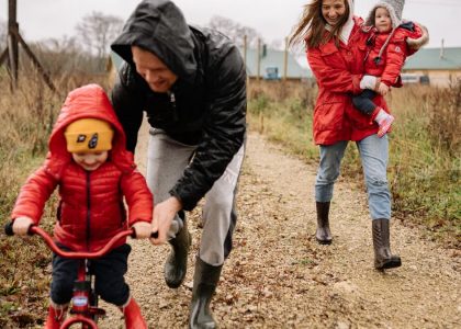 Family enjoying a joyful autumn walk along a rustic dirt road in vibrant outfits.
